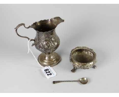 A Victorian silver relief decorated helmet cream jug together with a relief decorated silver salt on three-pad feet plus spoo