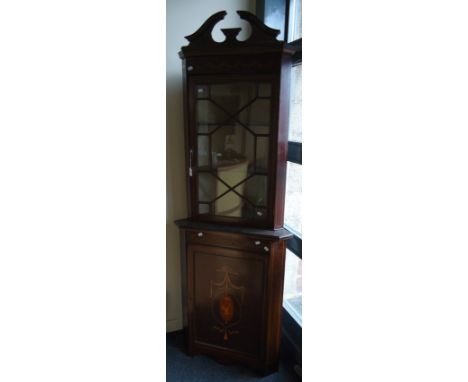 An Edwardian mahogany, boxwood inlaid and strung floor standing corner vitrine, having a broken scroll pediment over swagged 