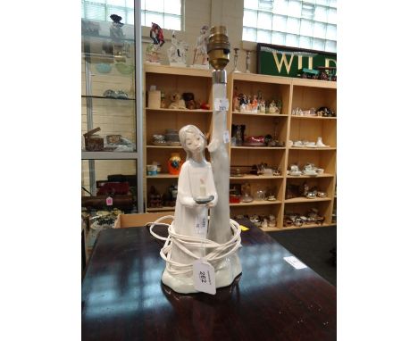 A Nao porcelain table lamp, modelled with a girl holding a chamber stick