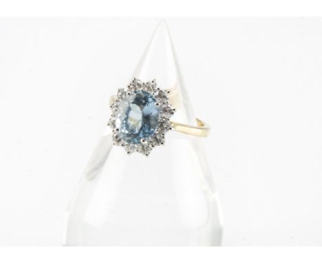 A modern 18ct gold aqua marine and diamond cluster ring, oval light blue stone of 2.6ct within brilliant cut surround, on hal