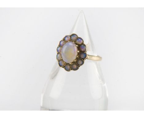 A modern 9ct gold and opal dress ring, having an oval opal surrounded by smaller round examples, hallmarked, 3.4g and size O 