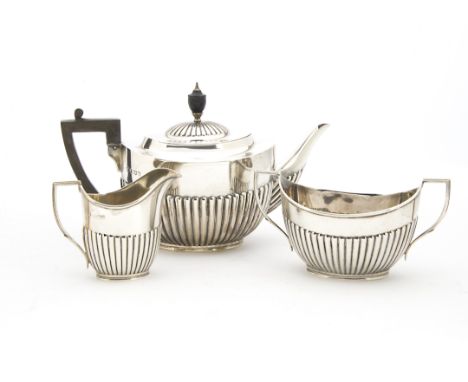 A George VI silver three piece silver tea set by William Hutton & Sons, helmet shaped with fluted lowers, having inscription 