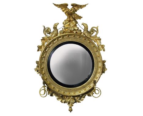 A Regency carved gilt wood framed convex wall mirror, with rockwork and eagle cresting, two further eagles with chain swags, 