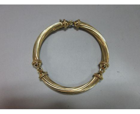 An unusual three link bangle stamped '750', each of the curved links a reeded spiral with ropetwist and hemisphere terminatio