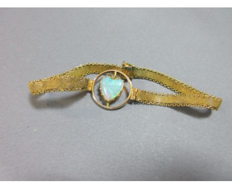 A heart-shaped opal set into a bracelet, the heart-shaped cabochon opal claw set in an open circular mount with hinged sides 
