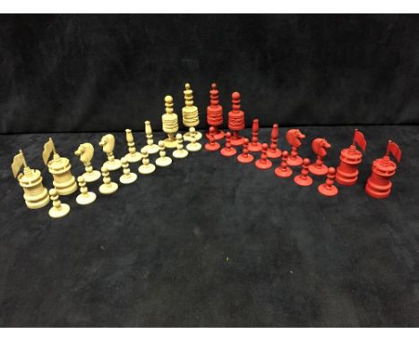 Two red and white part chess sets, one ivory, the other bone, the first with turned pieces, the king 8.5cm (3.25 in) high and