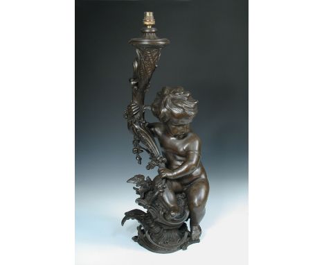 An early 20th century French rococo style bronzed spelter figural lamp, a cherub seated by a bird on the rocaille base holdin