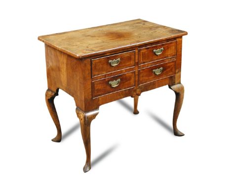 An early 18th century walnut lowboy, crossbanded border decoration to quartered veneers, fitted four small drawers on cabriol