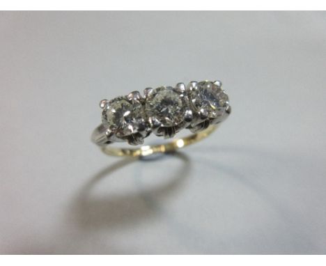 A three stone diamond ring, the three near uniform round brilliant cut diamonds claw set, and to chevron shoulders, of white 
