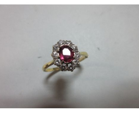 A ruby and diamond cluster ring, the oval cut ruby claw set in a border of ten round brilliant cut diamonds to a plain tapere