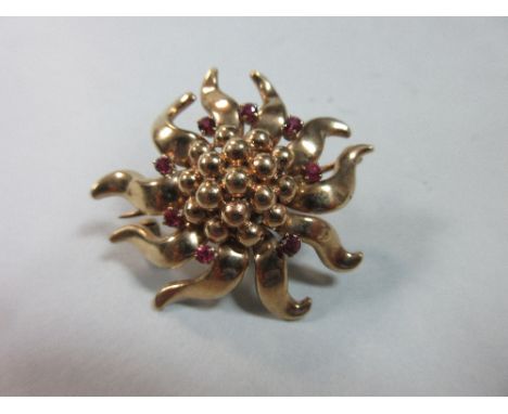 A gold and ruby flowerhead brooch, the anthers formed by a boss of gold beads surrounded by small round cut rubies at the bas