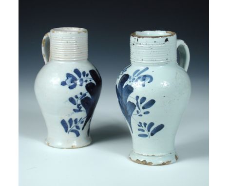 Two similar Delft blue and white jugs, possibly London circa 1780, each with reeded cylindrical necks above baluster bodies p