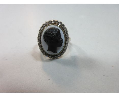 A Regency ring set with a hardstone cameo depicting a Blackamoor in a diamond surround, the banded agate carved with the blac