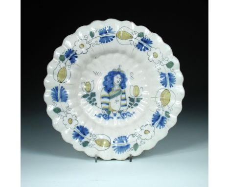 A late 17th century Delft dish commemorative of William III, yellow tulips flanking a portrait of the monarch central to gadr