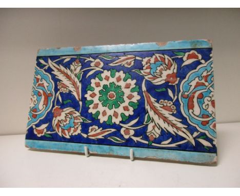 A 16th century Islamic Turkish Ottoman Iznik border tile, the central red and green rosette flanked by buds, saz leaves and h