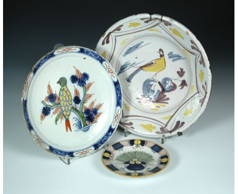 Three Delft polychrome plates, the centre of the first painted with a yellow bodied parrot perched in a red, green and blue t