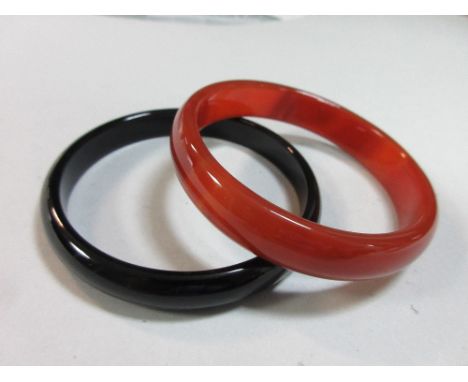 Two agate bangles, the first of lightly banded cornelian, width 1.3cm, internal diameter 6.5cm, the other of homogeneous blac