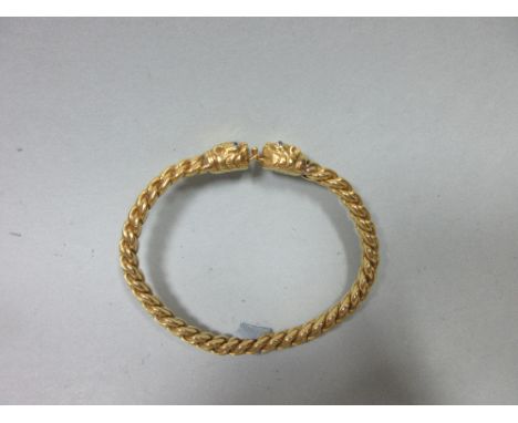 A diamond set plaited torque bangle, the thick wires plaited into a triangular cross-section terminating in cast dogs' or leo