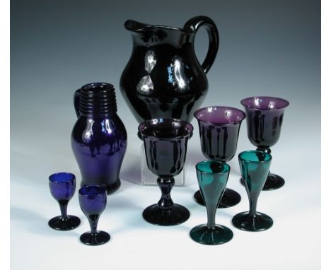 An aubergine glass jug, another blue, together with seven glasses, the first 18.5cm (7.25 in) high,the blue glass jug with tr