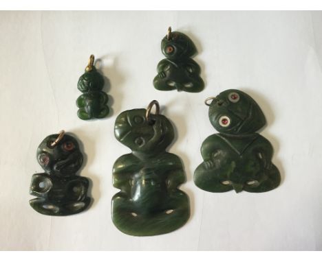 Five various carved green stone tikis, one with red jewelled eyes, 5cm (2 in) high, the largest and smallest with uncoloured 
