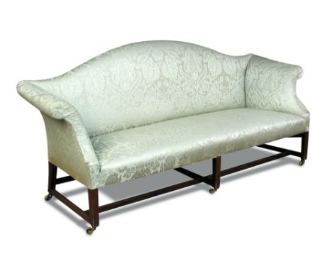 A late 18th century hump backed sofa, with scroll ends and upholstered in a green damask fabric, on stretchered square legs a