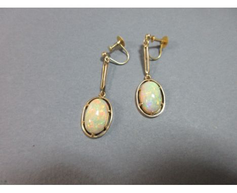 A pair of opal earpendants, each with a long oval cabochon opal displaying a full rainbow range of colour, claw set in a plai