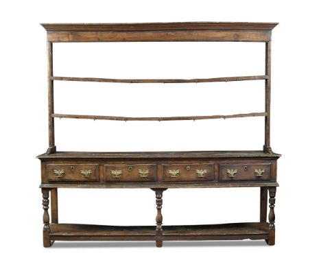 An 18th century oak dresser, with raised plate rack of two open shelves, iron cup hooks, the base fitted four drawers, later 