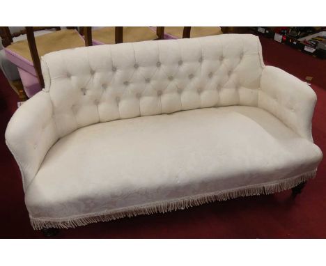 A late Victorian and later white floral fabric upholstered button back two seater salon sofa, raised on ring turned forelegs,