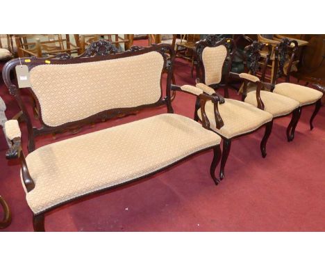 A late Victorian floral carved mahogany framed salon suite comprising two-seater sofa, width 132cm, elbow chair, and a pair o