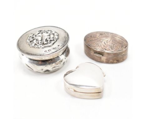 A group of three hallmarked silver lidded trinket boxes. The lot to include; a hinged lid of heart form, hallmarked for Londo