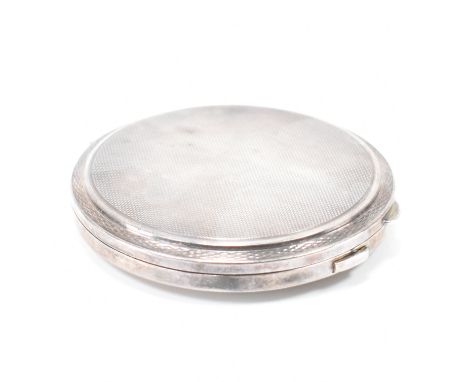 A vintage mid 20th Century silver hallmarked compact. The compact of round form with engine turned decoration, with mirror to