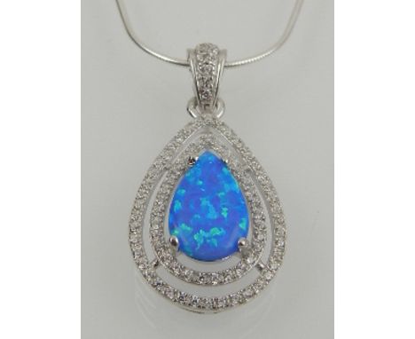 A silver, cubic zirconia, and blue opalite set pendant, suspended on a silver chain. 