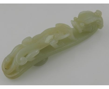 A Chinese celadon jade belt buckle, in the form of a dragon and panther. L. 11cm
