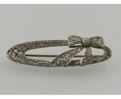 An Art Deco white metal and diamond set bar brooch, in the form of a bow within an oval mount. 