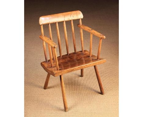 A 19th Century Comb Back Windsor Armchair. The top rail above six turned ash stick spindles; the outer two piercing through t