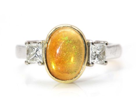 An 18ct yellow and white gold three stone fire opal and diamond ring,with an oval cabochon fire opal, rub set in a yellow col