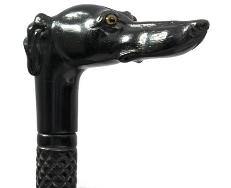 A CARVED EBONY WALKING STICK, the grip carved as a greyhound's head with inset glass eyes, the shaft crosshatched and wrythen