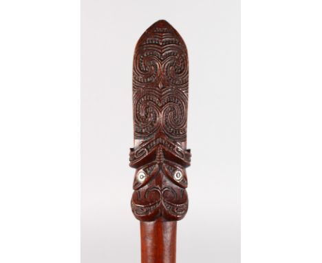 A GOOD MAORI WOODEN PADDLE of good colour, with carved top with two mother-of-pearl eyes either side, 2-inches wide at the ba