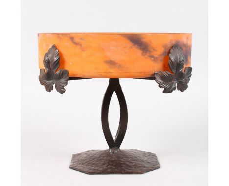 AN ART DECO MOTTLED ORANGE CIRCULAR FRUIT BOWL. Signed.  9.5ins diameter, on a cross framed metal stand with vine leaves.