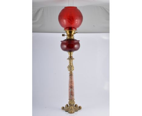 Brass oil lamp, marble column, ruby glass reservoir with a red tinted shade complete with chimney, 91cm.