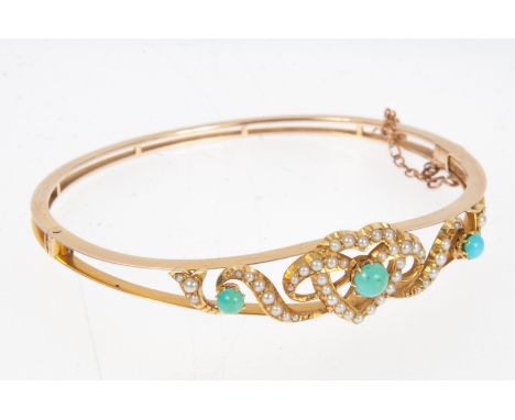 A yellow metal half hinged bangle in the Edwardian style, the two bars to the front holding a seed pearl and turquoise heart 