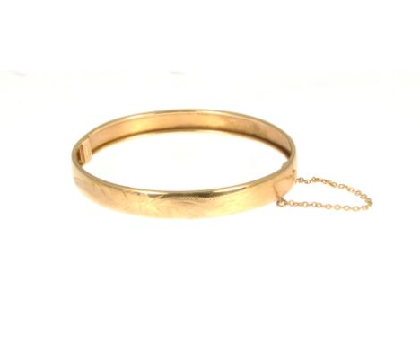 A 9 carat yellow gold half hinged bangle, 8mm wide, engraved pattern to front, approximate weight 10.8gms.
