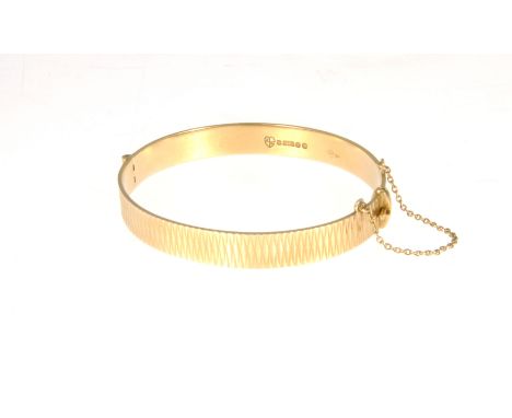 A 9 carat yellow gold solid half hinged bangle, 8.5cm wide, bright cut design, hallmarked London 1966, internal dimensions 60