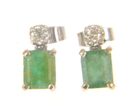 A pair of emerald and diamond earstuds, one brilliant cut diamond four claw set to each supporting a faceted emerald cut one 