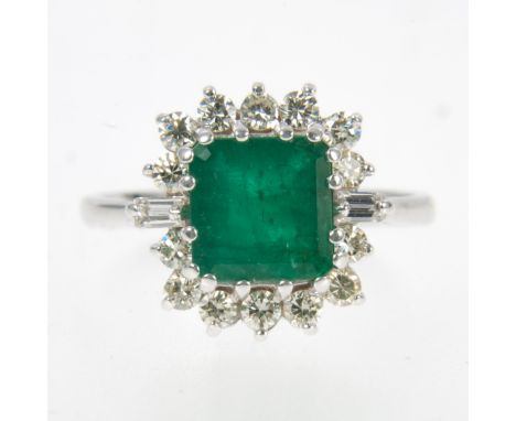 An emerald and diamond square cluster ring, the 8.1mm square step cut emerald, claw set and surrounded by fourteen brilliant 