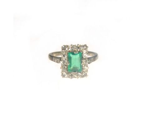 A green stone and diamond rectangular cluster ring, the rectangular step cut green stone 7.4mm x 5.3mm, surrounded by fourtee