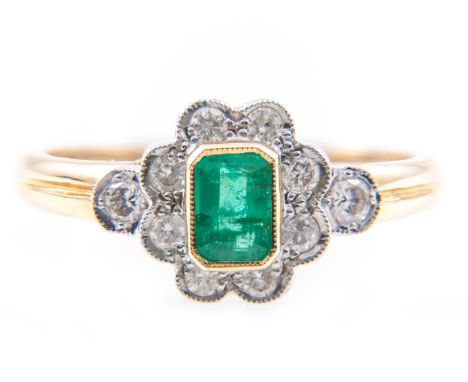 An emerald and diamond rectangular cluster ring, the rectangular step cut emerald 4.5mm x 3mm, surrounded by eight pip claw a