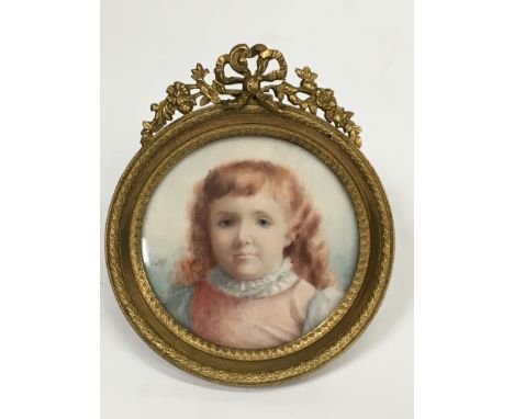 A 19th century miniature portrait of a Young Girl in pink dress with long auburn hair in circular Ormolu frame.