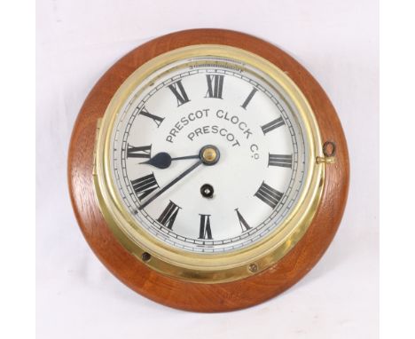 Prescot Clock Company brass bulkhead timepiece, with Roman enamel dial, mounted on a mahogany plinth, 30cm.   CONDITION REPOR
