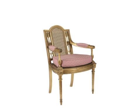 AN EDWARDIAN PERIOD GILTWOOD FRAMED ARMCHAIR, in the Louis Seize taste, the arch top cane panel back flanked by twin ribbon t